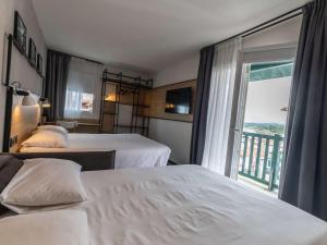 um quarto de hotel com duas camas e uma janela em ibis Ciboure Saint-Jean-de-Luz em Ciboure