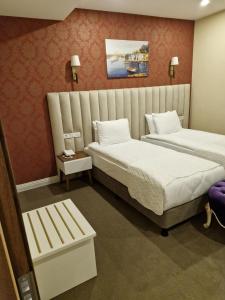 a hotel room with two beds and a bench at Mr BEYAZ HOTEL in Istanbul