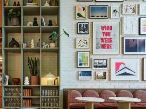 Cette chambre est dotée d'un mur avec des photos et des tables. dans l'établissement TRIBE London Canary Wharf, à Londres