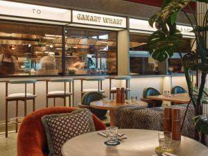 um restaurante com mesas e cadeiras e um balcão em TRIBE London Canary Wharf em Londres