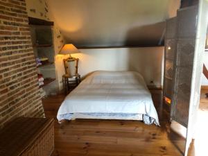 um quarto com uma cama num quarto com uma parede de tijolos em Bassin aux nénuphars em Crux-la-Ville