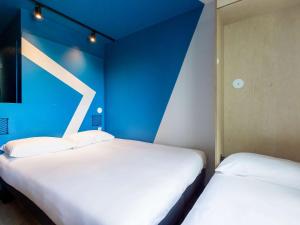 Duas camas brancas num quarto com paredes azuis em ibis Budget La Rochelle Centre em La Rochelle