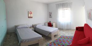 マテーラにあるCasa Vacanze La Perlaのベッドルーム1室(ベッド2台、ソファ、窓付)