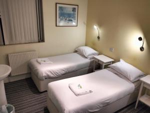 Habitación de hotel con 2 camas y lavamanos en Manor Hotel en Londres