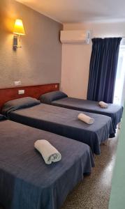 three beds in a room with blue sheets at SB Arenal in El Arenal