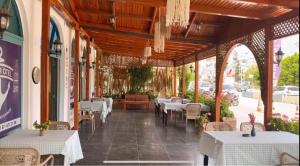 un restaurante vacío con mesas y sillas blancas en ÖZTUR OTEL YUMURTALIK, en Yumurtalık