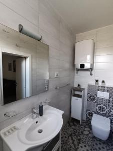 a bathroom with a sink and a toilet and a mirror at Faveria Apartments Amphitheater with FREE Parking in Pula