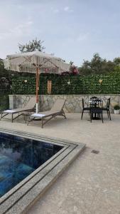 un patio con mesa y sombrilla junto a la piscina en Vila Malo 2, en Ksamil