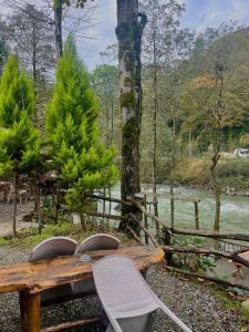 a wooden table and chairs next to a river at Yaşam Bungalows Otel in Çamlıhemşin