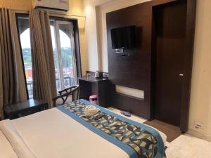 a hotel room with a bed and a flat screen tv at HOTEL JODHA THE GREAT in Agra