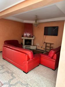 a living room with two red couches and a television at Villa hay Salam in Sale