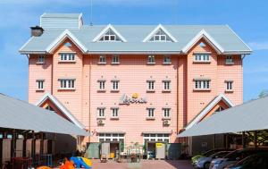 un grande edificio rosa con macchine parcheggiate di fronte di Ikaho Kids Paradise Hotel - Vacation STAY 56430v a Shibukawa