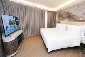 Hotel Santika Premiere Lampung في بندر لامبونغ: غرفة فندقية بسرير وتلفزيون بشاشة مسطحة