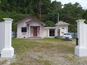 una casa blanca con un coche aparcado delante de ella en Tiny House Idaman Kuala Terengganu with Private House en Kuala Terengganu
