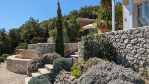 a garden with a stone retaining wall and stairs at Die Drei Grazien, luxuriöse Villa mit eigenem Pool in Katouna