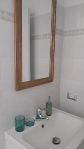 a bathroom sink with a mirror and two green cups on it at Casa Platina in Cremona +8 photos