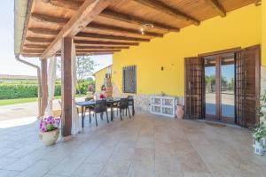 patio ze stołem i krzesłami oraz żółtą ścianą w obiekcie La casa di Lola w mieście Monterosi
