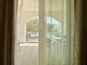 okno z widokiem na stół i krzesła na balkonie w obiekcie Herceg Novi w mieście Herceg Novi