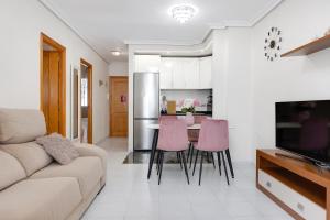 - un salon avec un canapé et une table avec des chaises roses dans l'établissement urb ViñaMar, à Torrevieja