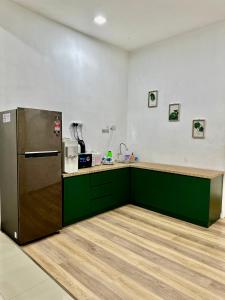 uma cozinha com armários verdes e um frigorífico em The Amore Homestay Klebang, Melaka em Malaca