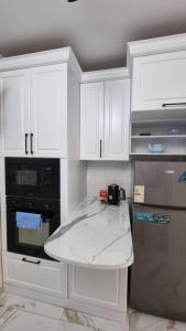 une cuisine avec des armoires blanches et un appareil noir dans l'établissement Sam Rental 1, à Samarcande