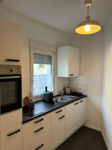 a kitchen with white cabinets and a sink and a television at Apartment für 2 Personen in Wiesbaden