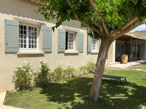 Un banco sentado debajo de un árbol frente a un edificio. en LAVENINE a Modène, en Modène