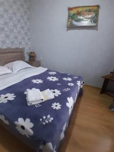 a bed with a blue blanket with white flowers on it at Akhaltsikhe hotel “Sunny House” in Akhaltsikhe