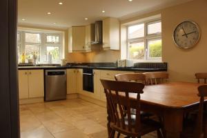 a kitchen with a table and a clock on the wall at Helene - Dog Friendly Family Home on Norfolk Coast in Potter Heigham