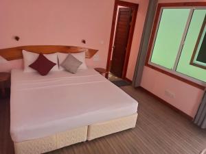białe łóżko w pokoju z oknem w obiekcie MAMELLO Beach Club Maldives w mieście Feridhoo