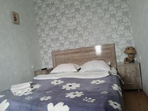 a bed with a blue comforter with white flowers on it at Akhaltsikhe hotel “Sunny House” in Akhaltsikhe