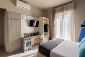 1 dormitorio con 1 cama y escritorio con TV en Hotel Nina en Marina di Bibbona