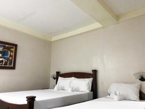 1 dormitorio con 2 camas con sábanas blancas en Palawan Rose Garden 1, en Puerto Princesa City