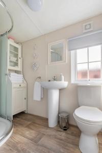 a white bathroom with a sink and a toilet at Poppy Lodge Glendevon Scotland in Glendevon