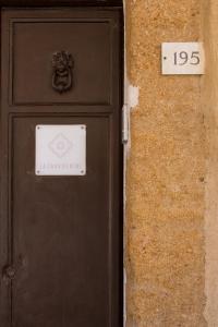 een zwarte deur met een bord naast een stenen muur bij La Casa di Ninì in Agrigento
