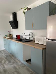 a kitchen with blue cabinets and a white refrigerator at Le petite maison de la Motte in Doué-la-Fontaine