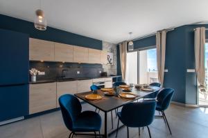 a kitchen with a dining table and blue chairs at Luxury Mind Vue Exceptionnelle Pied dans l'eau Parkings privés 2 places Climatisation Hyper centre logement d'exception in La Grande-Motte