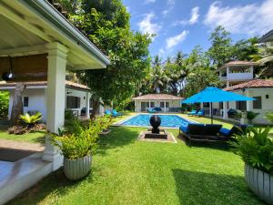 a backyard with a swimming pool and a house at Thalpe Bungalows in Unawatuna