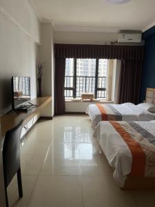 um quarto de hotel com duas camas e uma secretária e uma janela em 广州朴宿漫享公寓(琶洲国际会展中心店） em Guangzhou