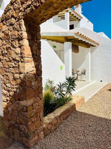 uma casa branca com uma parede de pedra em Can Chumbera Formentera em Cala Saona