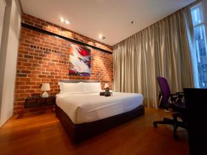 um quarto com uma parede de tijolos e uma cama em Soho Suites KLCC by Alucard's Cat em Kuala Lumpur