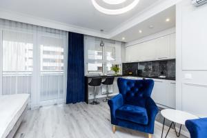 a living room with a blue chair and a kitchen at Premium Glamour Apartment by Krakow Home in Kraków