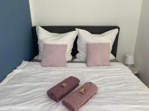 ein Bett mit zwei Kissen und lila Handtüchern darauf in der Unterkunft Deluxe Apartment mit Stil - Carport Stellplatz - Küche - NETFLIX in Oldenburg