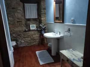 a bathroom with a sink and a stone wall at Palacio de Cantiz in Becerreá