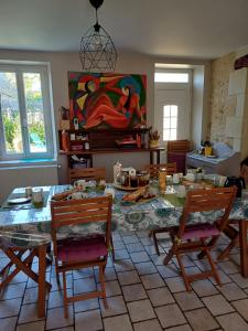 a living room with a table with chairs and a painting at la pause zen in Saint-Georges-sur-Cher