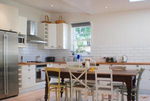 a kitchen with a wooden table and white cabinets at Illalangi Boutique Cottage in Blackheath