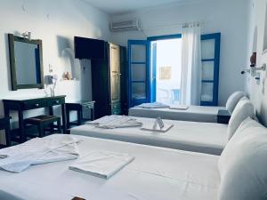 a room with two beds and a desk and a mirror at Pelagos Studios in Parikia