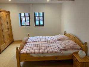 1 Schlafzimmer mit einem Bett mit gestreifter Decke und 2 Fenstern in der Unterkunft Schloßbergwohnung Löwenhaus in Homberg