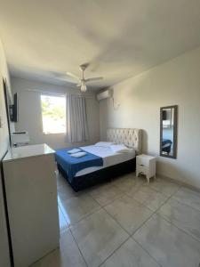 Schlafzimmer mit einem Bett, einem Spiegel und einem Fenster in der Unterkunft Flat centro in Ubá