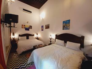 1 dormitorio con 2 camas y TV de pantalla plana en Palais Al Firdaous, en Fez